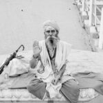 A Sadhu in traditional clothing raises his hand in blessing at a Varanasi ghat, India.
