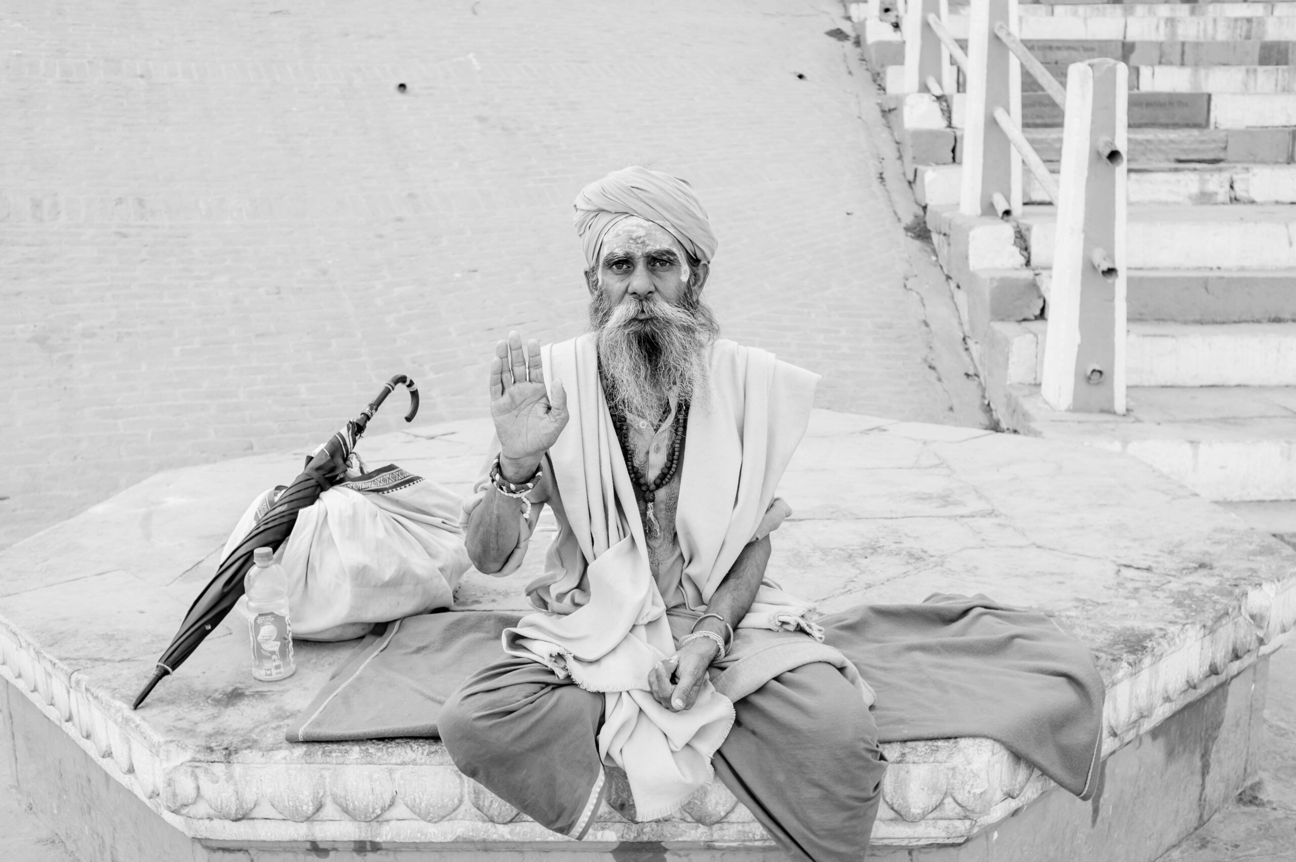 A Sadhu in traditional clothing raises his hand in blessing at a Varanasi ghat, India.