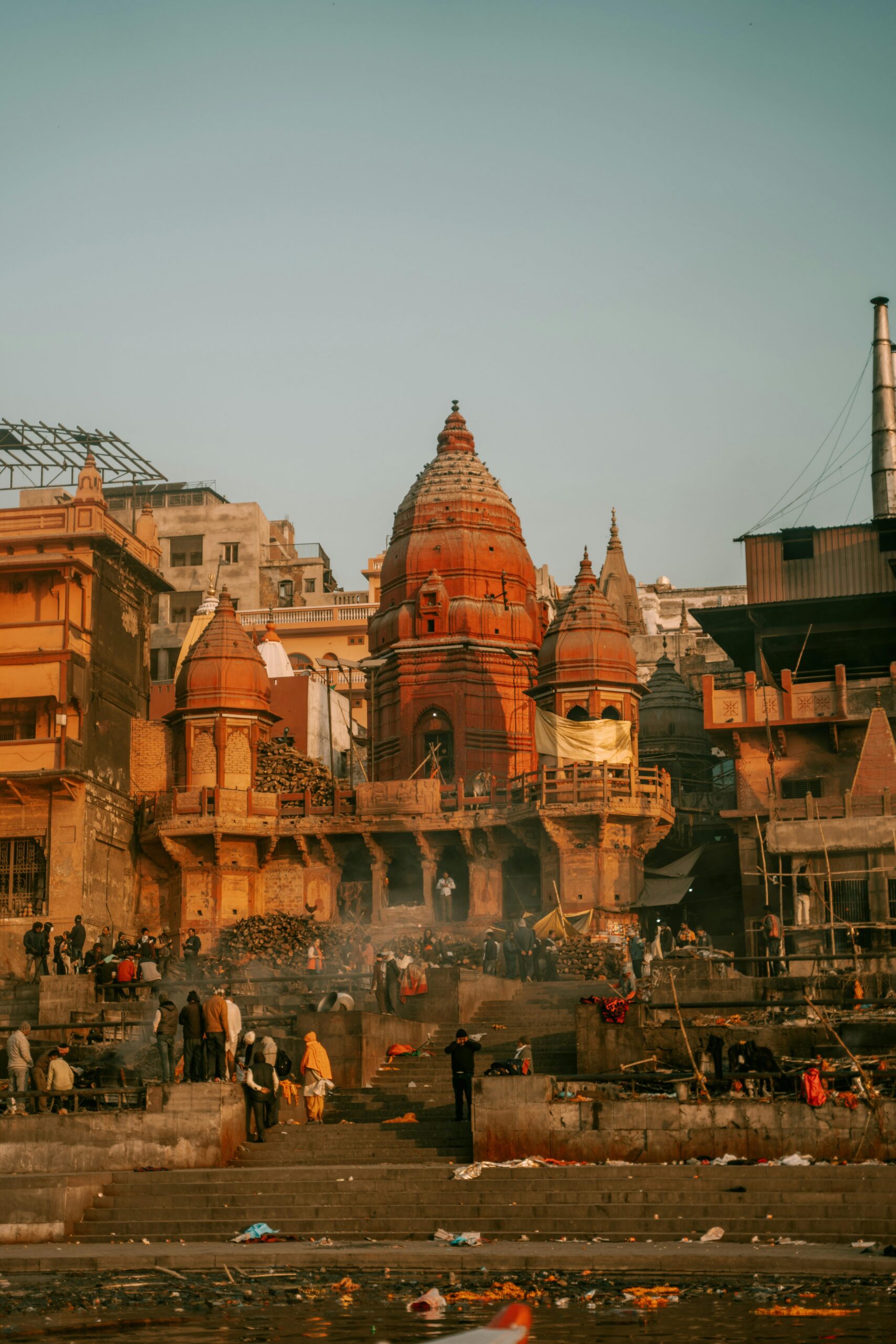 Crowd gathers near a historic temple in Varanasi, India at sunrise. Iconic architecture.