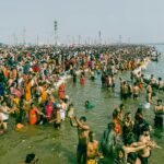 A large crowd participates in ritual bathing at the confluence of the Ganges River in Prayagraj, India.