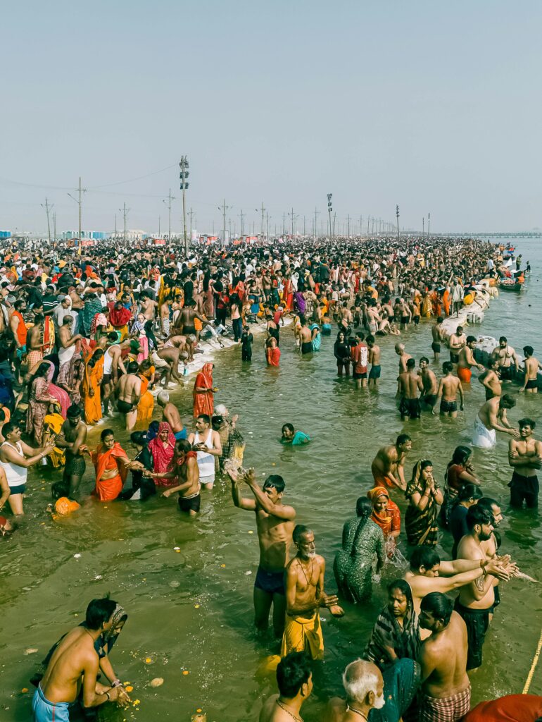 A large crowd participates in ritual bathing at the confluence of the Ganges River in Prayagraj, India.